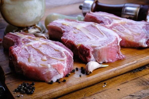 Tahta arka planda pirzola ve taze çiğ domuz filetosu.