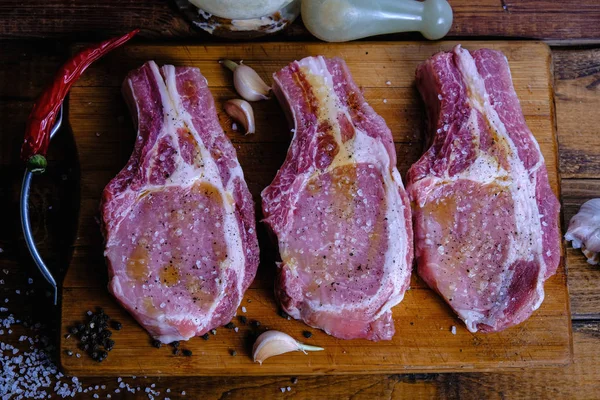 Tahta arka planda pirzola ve taze çiğ domuz filetosu.