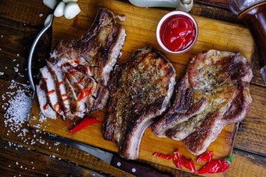 Ahşap arka planda pirzola ve kızarmış domuz filetosu.