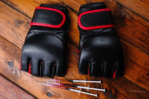 Ahşap bir arka planda mma eldivenleri ve steroid ilaç bileşimi