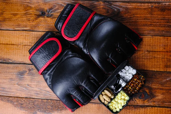 Ahşap bir arka planda spor besin bileşimi içeren mma eldivenleri ve steroid ilaçları.