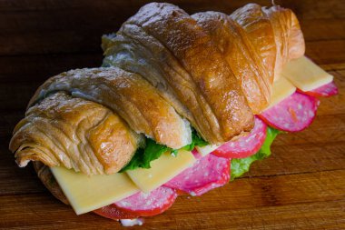 Ahşap arka planda izole edilmiş jambonlu ve peynirli kruvasan.