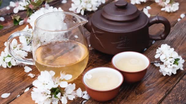 Китайська чайна церемонія композиції на дерев'яному тлі з вишневим листям. — стокове відео