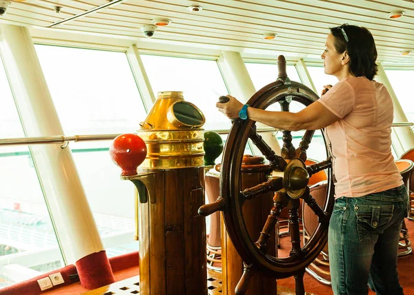 Woman at the wheel of a ship.