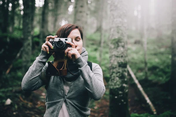 Mulher com câmera vintage tirando foto na floresta — Fotografia de Stock