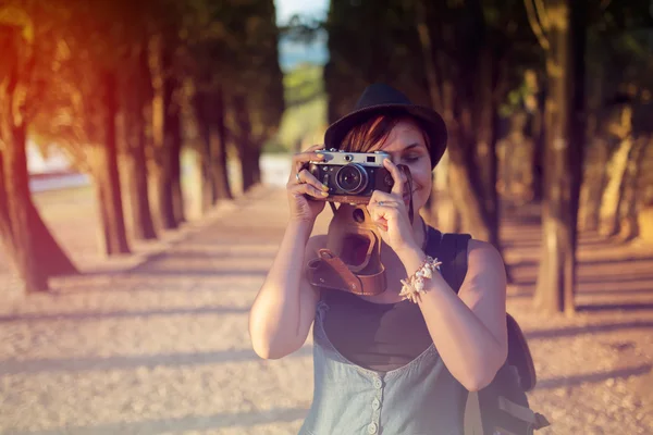 Mulher com câmera vintage no beco do parque ao pôr do sol — Fotografia de Stock