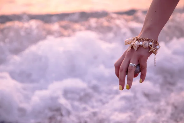 Woman holding stone near sea at sunset — Stock Photo, Image