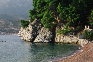Çakıl deniz sahil yakınında taş dağ ve orman gün batımında