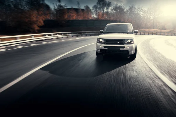 Voitures Land Rover Range Rover rouler sur la route asphaltée de la ville à l'automne ensoleillé de jour — Photo