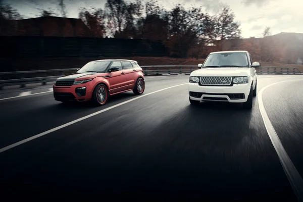 Auto's Land Rover Range Rover rijden op asfalt stad weg bij herfst zonnig overdag — Stockfoto