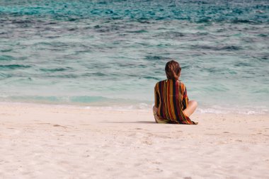 Kadın tropikal kum plajı üzerinde oturuyor