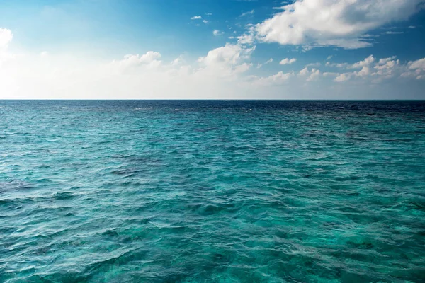 昼間で透明な水を青い曇り空の地平線 — ストック写真