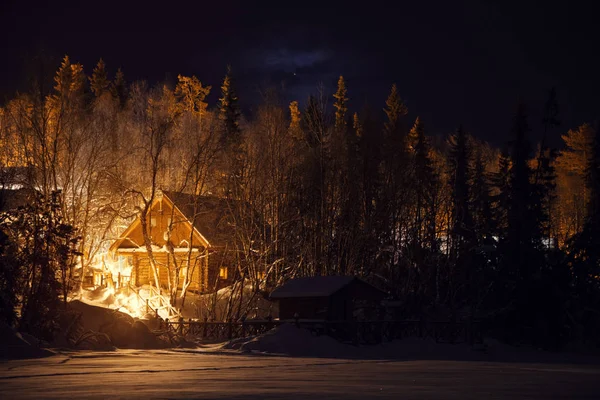 Casa de madera en el bosque nevado en la noche de invierno — Foto de Stock