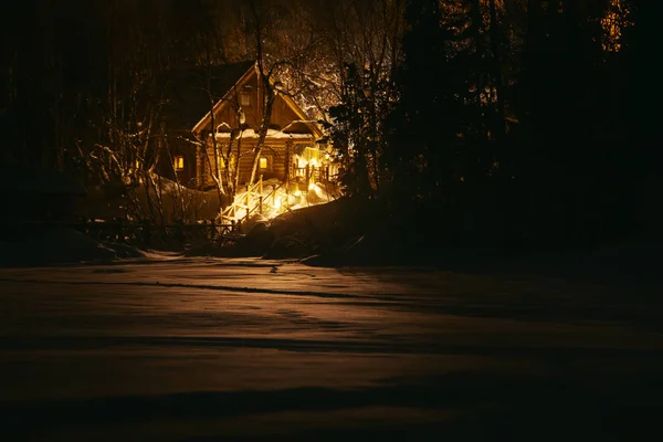 Houten huis in het besneeuwde bos in de winternacht — Stockfoto