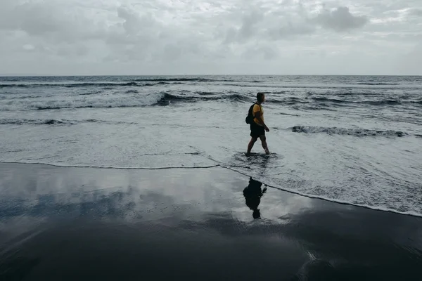 Una donna sta camminando sulla spiaggia. Cielo riflesso sulla sabbia bagnata . — Foto Stock