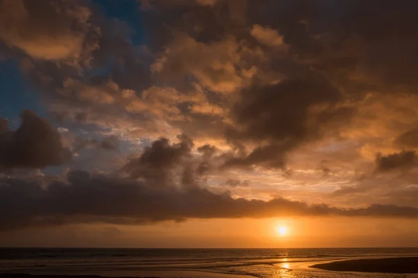 Dramático pôr-do-sol nuvens refletidas no mar de água . — Fotografia de Stock