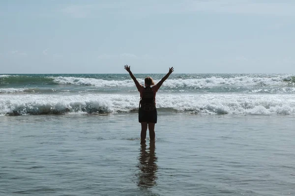 Eller yukarı deniz kumsalda bir kadındır. Uzanmış silah kaldırdı. 