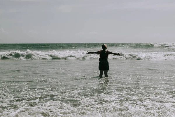 La donna è in piedi sulla spiaggia di mare. Braccia tese sollevate . — Foto Stock