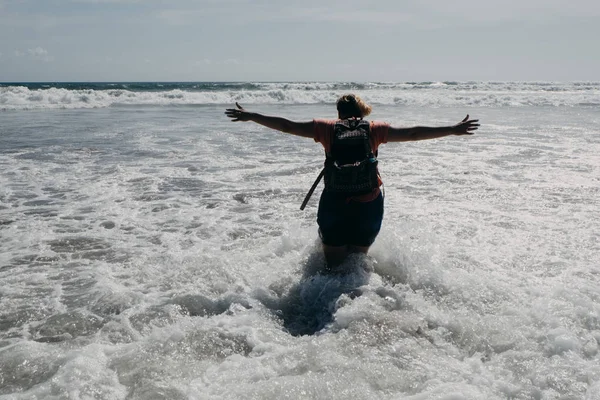 La donna è in piedi sulla spiaggia di mare. Braccia tese sollevate . — Foto Stock