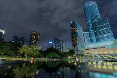 Şehir merkezindeki iş bölgesinin arka plan, gökdelenler suya yansıyan. Kuala Lumpur City Centre Park geceleri