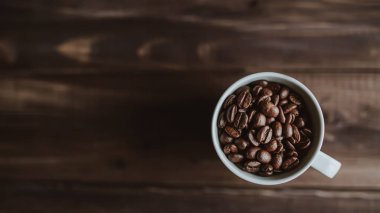 Kavrulmuş kahve çekirdekleri ahşap arka plan, beyaz Kupası