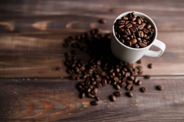 Kavrulmuş kahve çekirdekleri ahşap arka plan, beyaz Kupası