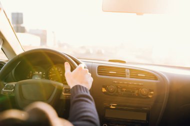 Adam araba günbatımında kullanıyor. İç iç görünüm. Direksiyon simidi ellerde