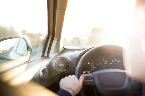 Man is driving car at sunset. Inside interior view. Hands on steering wheel — Stock Photo, Image