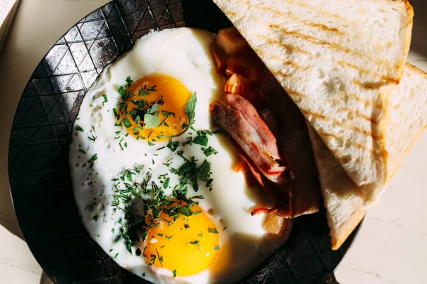 Жареные яйца, бекон, тосты. Классический завтрак в железной сковороде — стоковое фото