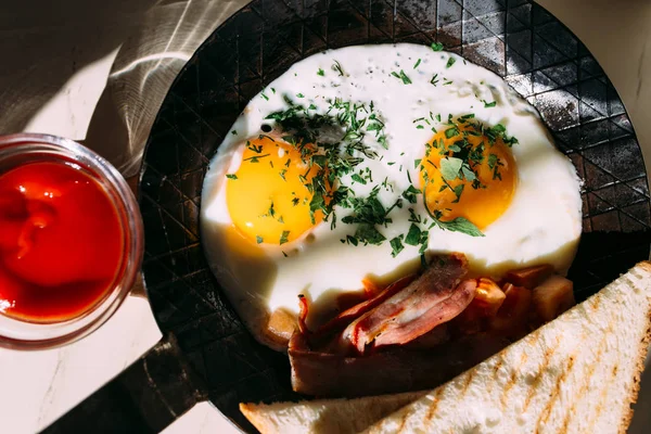 Ovos fritos, bacon, tomates na torrada. Comida clássica de pequeno-almoço em panela de ferro — Fotografia de Stock
