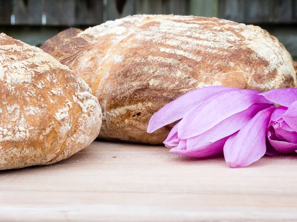 Two round breads on a wooden board with magnolia flowers — Stock Photo, Image
