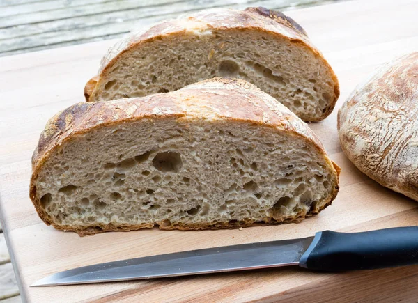 Cut round bread on a wooden board with knife — Stock Photo, Image