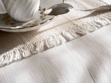 Fincan, çay kaşığı ve çay kaşığı beyaz masa örtüsü