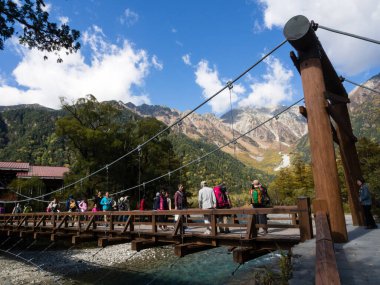 Matsumoto, Japonya - 7 Ekim 2015: Resimli Kamikochi Vadisi 'ndeki Kappa-bashi köprüsünü geçen turistler