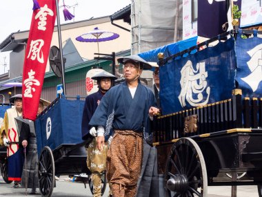 Takayama, Japonya - 10 Ekim 2015: Geleneksel kostümlü yerel halk, geleneksel Takayama Sonbahar Festivali sırasında eski şehrin dar sokaklarında festival arabalarını çekiyorlar