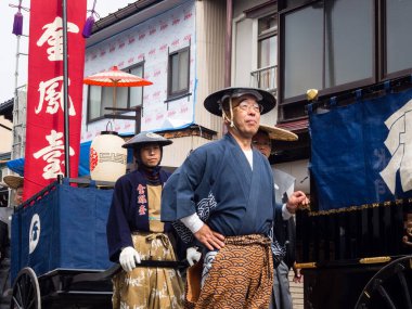 Takayama, Japonya - 10 Ekim 2015: Geleneksel kostümlü yerel halk, geleneksel Takayama Sonbahar Festivali sırasında eski şehrin dar sokaklarında festival arabalarını çekiyorlar