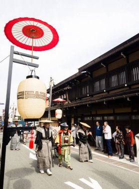 Takayama, Japonya - 10 Ekim 2015: Geleneksel kostümlü yerel halk, geleneksel Takayama Sonbahar Festivali sırasında eski şehrin dar sokaklarında festival arabalarını çekiyorlar