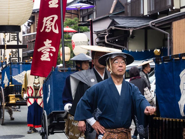 高山市 2015年10月10日 高山秋祭りのパレード中に高山旧市街の狭い通りに沿って祭りのカートを引く伝統的な衣装の地元の男性 — ストック写真