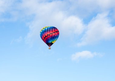 Washington eyaletindeki Winthrop Balon Festivali 'nde mavi gökyüzünde yumuşak bulutlarla uçan renkli sıcak hava balonu.