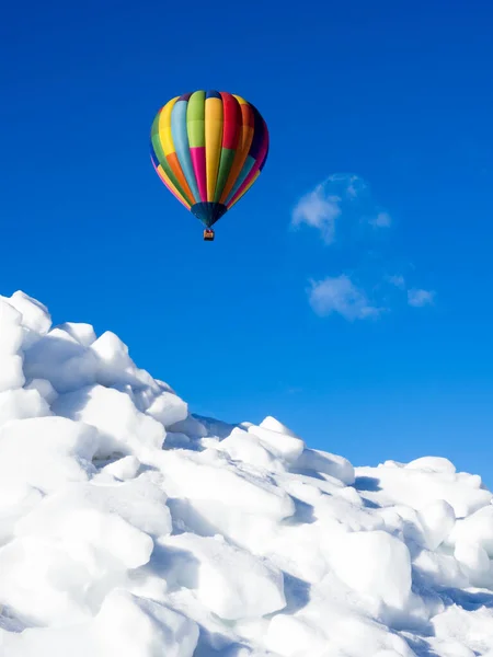 Kışın karlı arazide uçan renkli sıcak hava balonu