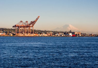 Seattle, WA, ABD - 1 Nisan 2016: Günbatımında Seattle limanında kargo vinçleri ve arka planda Rainier Dağı