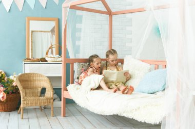 Ablası küçük kız kardeşine kitap okuyor.