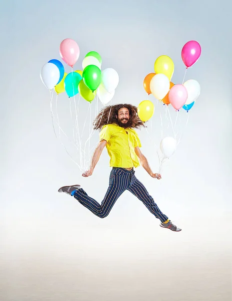 Retrato conceitual de um homem infantil pulando com balões — Fotografia de Stock
