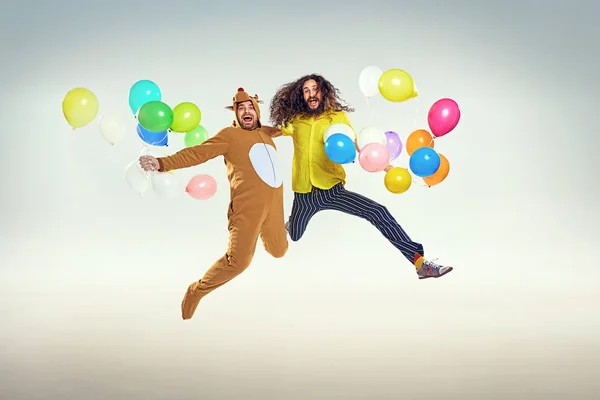 Представьте двух забавных парней, прыгающих и держащих воздушные шары — стоковое фото