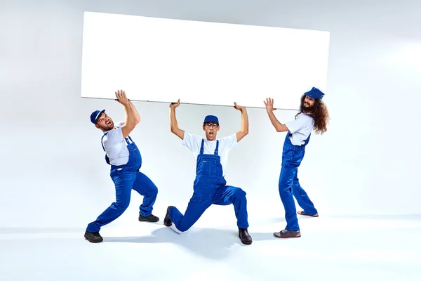 Lustige Handwerker, die ein schweres Handelsbrett heben — Stockfoto