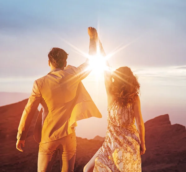 Casal ambicioso olhando para o pôr do sol com um gesto vitorioso — Fotografia de Stock