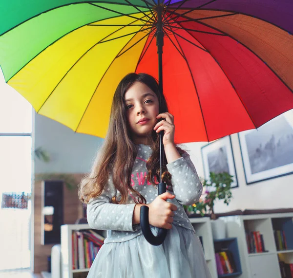 一个可怜的小女孩在房子里拿着一把彩色雨伞的画像 — 图库照片