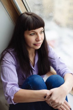 Güzel bir orta yaşlı kız pencere pencere yanında oturur.