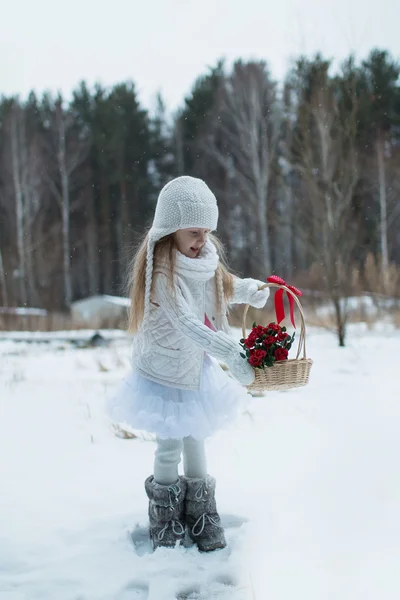 Niedliches kleines Mädchen mit Blumen in einem Korb kalten Wintertag — Stockfoto