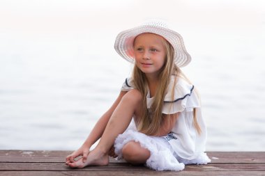 güzel kız beyaz şapka ve beyaz elbise gölde iskelenin üzerinde oturan